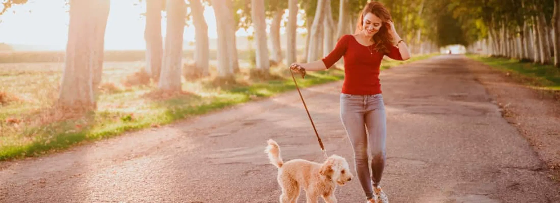 Nuori nainen kävelyttämässä koiraansa ulkona iloisena löydettyään 4000 lainan Axolainan kautta
